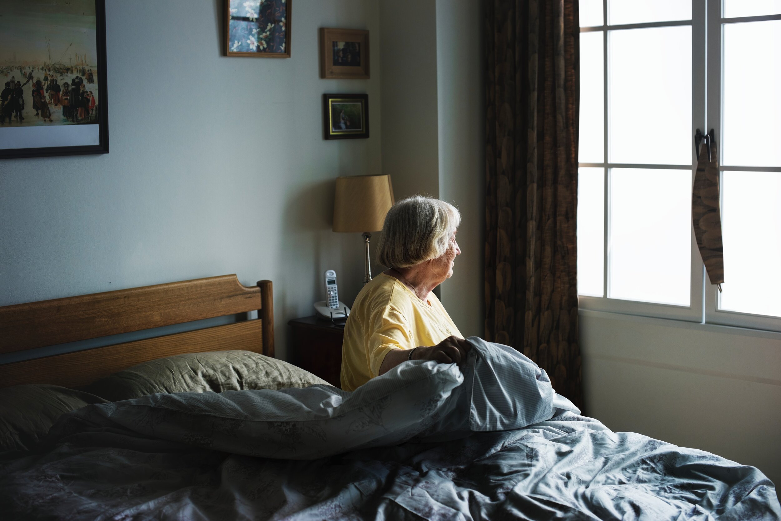 elderly woman looking out the window from her bed.jpg