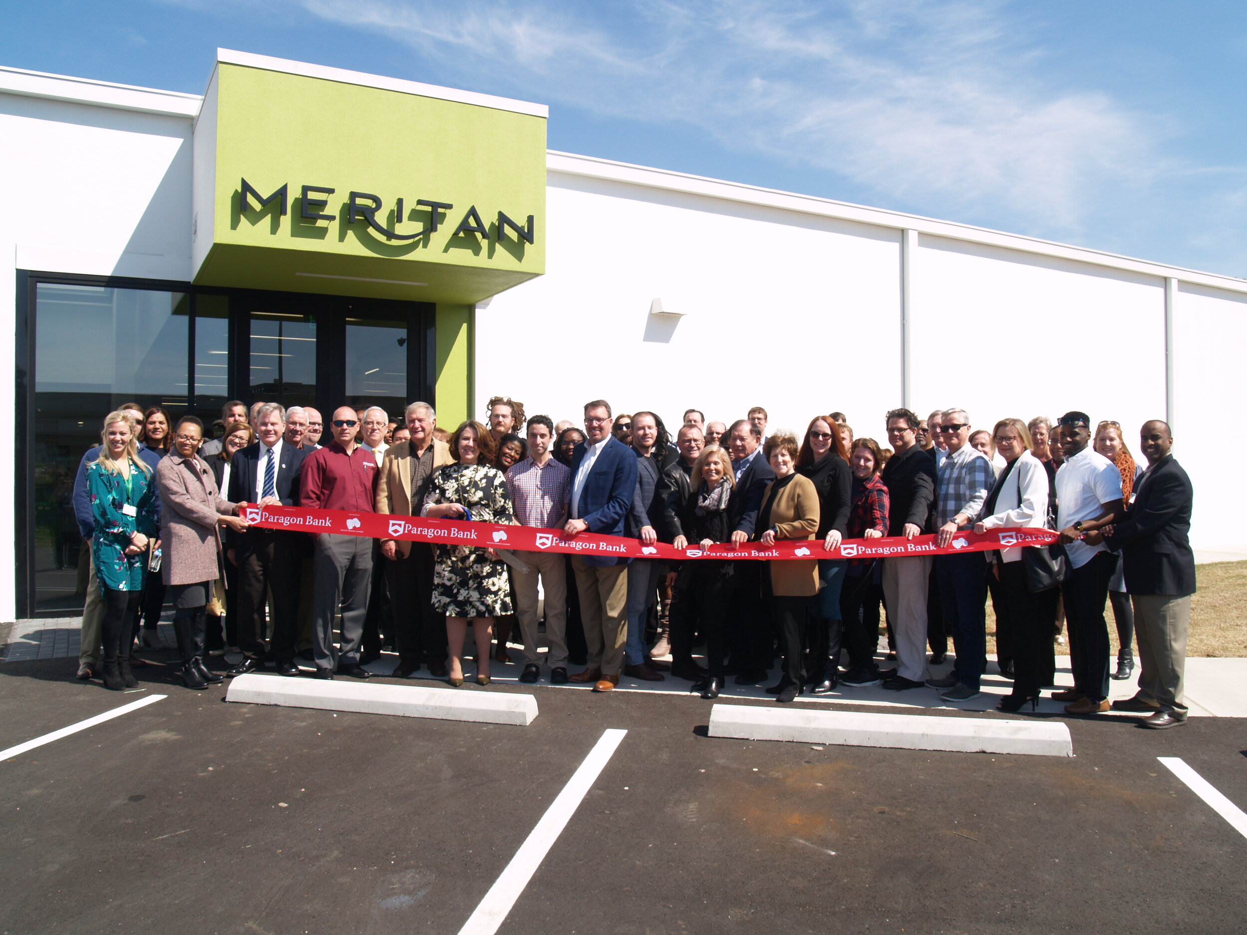 Large group cutting the ribbon to Meritan's new building in 2017