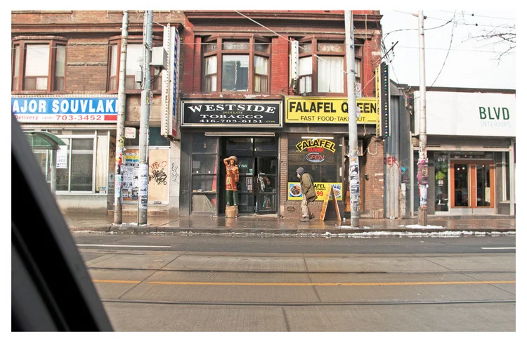 Toronto, Ontario, drive-by view of Cigar store Indian and street person, Queen St and Bathurst