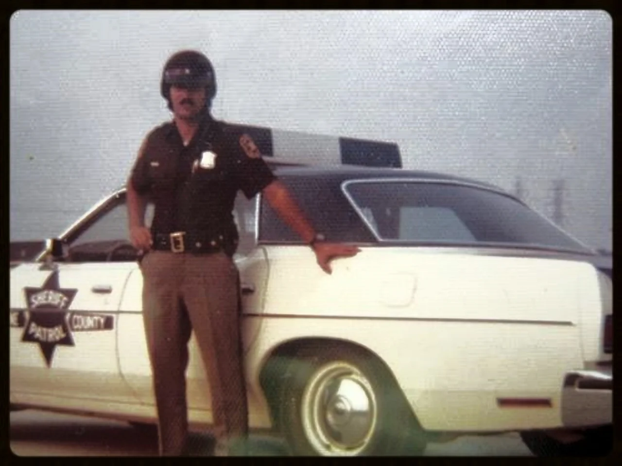 Thursday, July 19, 1973. Assigned to our Patrol and Investigation Division. I loved cruising the county. One Sunday morning as I drove a major highway I got into a chase with a woman and stopped her by shooting out her right tires with my .357 magnum. Her car was full of clothes and she was enraged at her husband so she took it out at me, biting and clawing until I dragged her out of the car as churchgoers stopped and gawked. Wives can be great companions and lots of fun, but from a cop's perspective, an angry wife can be something else all together. She can stop your heart. At a traffic accident one rainy night, placing flares in the road, another enraged housewife sped off without her glasses directly into the accident scene. I saw a pair of headlights bracketing me, one on the right and one on the left, barreling right at me. All I could do was leap straight up in the air. Her bumper caught me in both calves and I could hear her shrill screams as I reverse-somersaulted over her hood, windshield, roof, and trunk. I bounced off the pavement, saw a flash of light; then everything went black. 