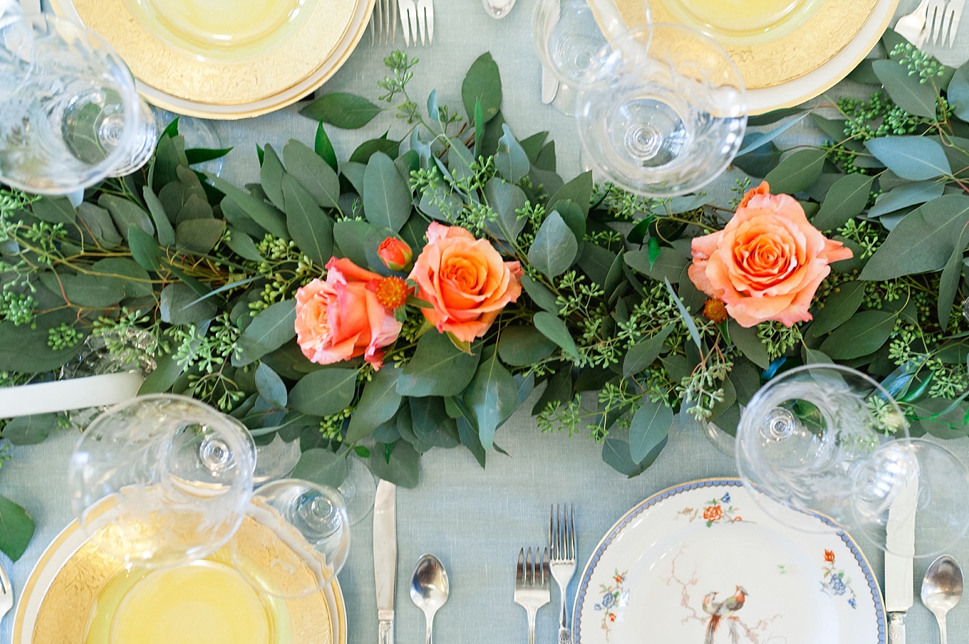 A lush runner of seeded eucalyptus with minimal accents of orange roses decorating the head table (photo by Roots of Life ). 