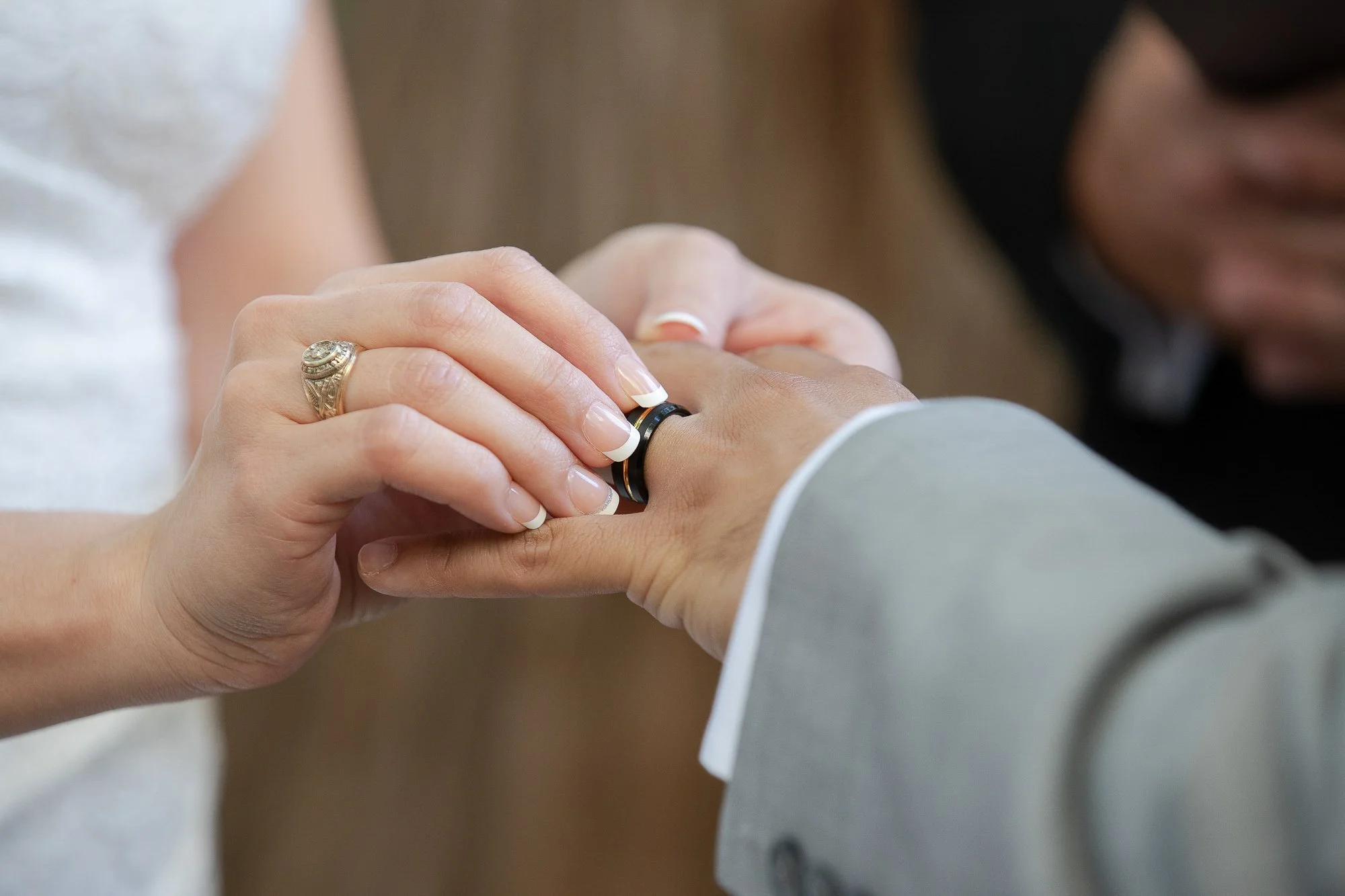 Close-up of a wedding ring being placed on a person's finger during a wedding ceremony.