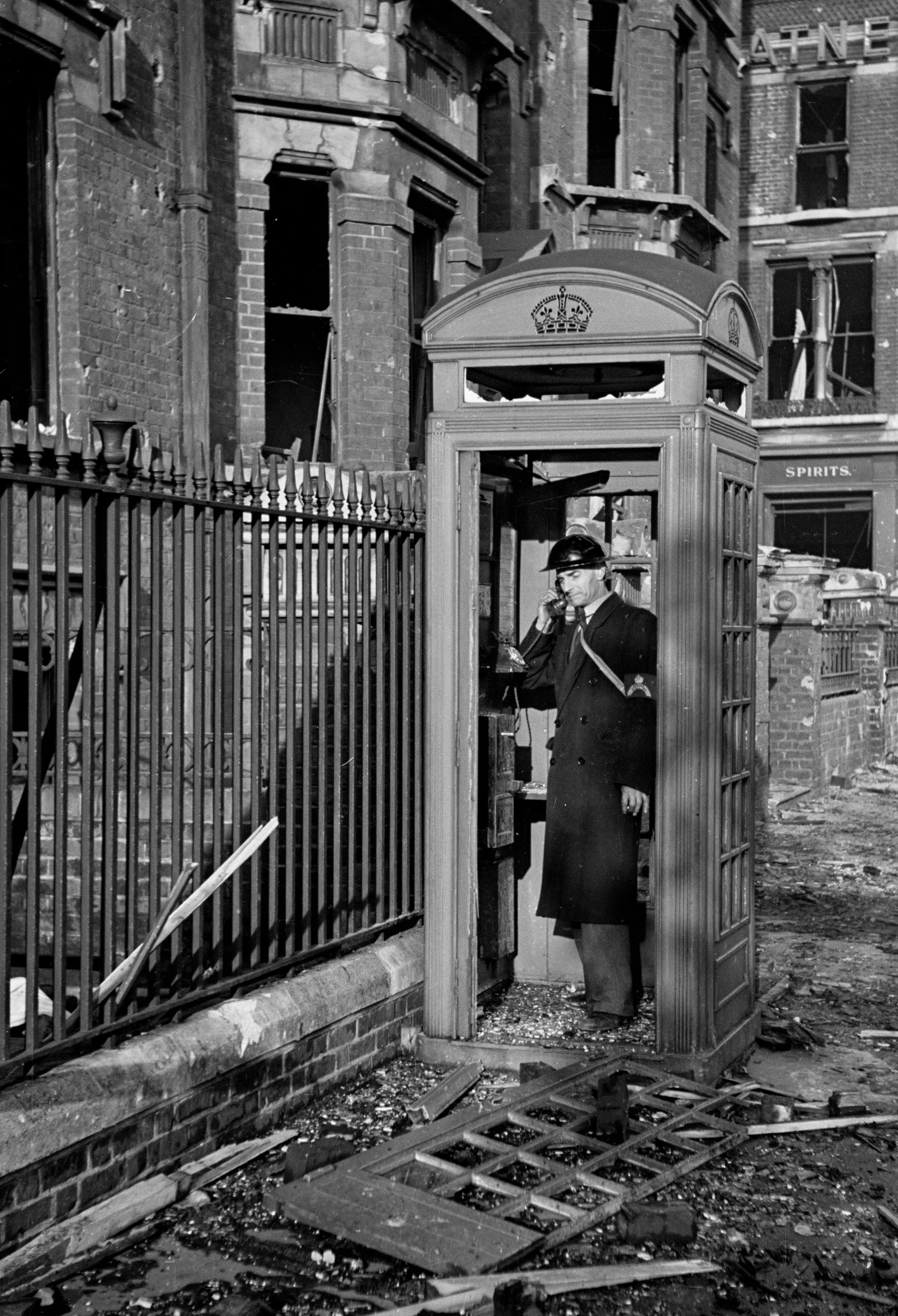 Air-raid warden telephones from a damaged phone booth, London 1940
