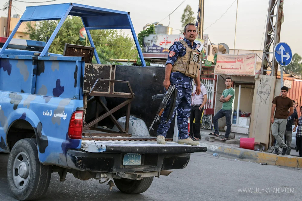 A Kirkuk police officer warily watches the scene. Tension is high and tempers have been flaring up. Moments earlier, Peshmerga soldiers fired their weapons into the air to scatter onlookers. Photograph by Lucy Kafanov.