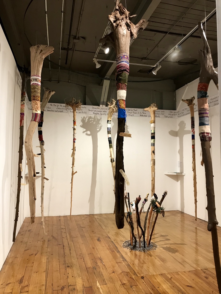   Around The World: Unity in Diversity,  2017 - 2018 12 driftwood tree trunks, multi-cultural fabrics, paper ”barks" Installation view at the Red Head Gallery 