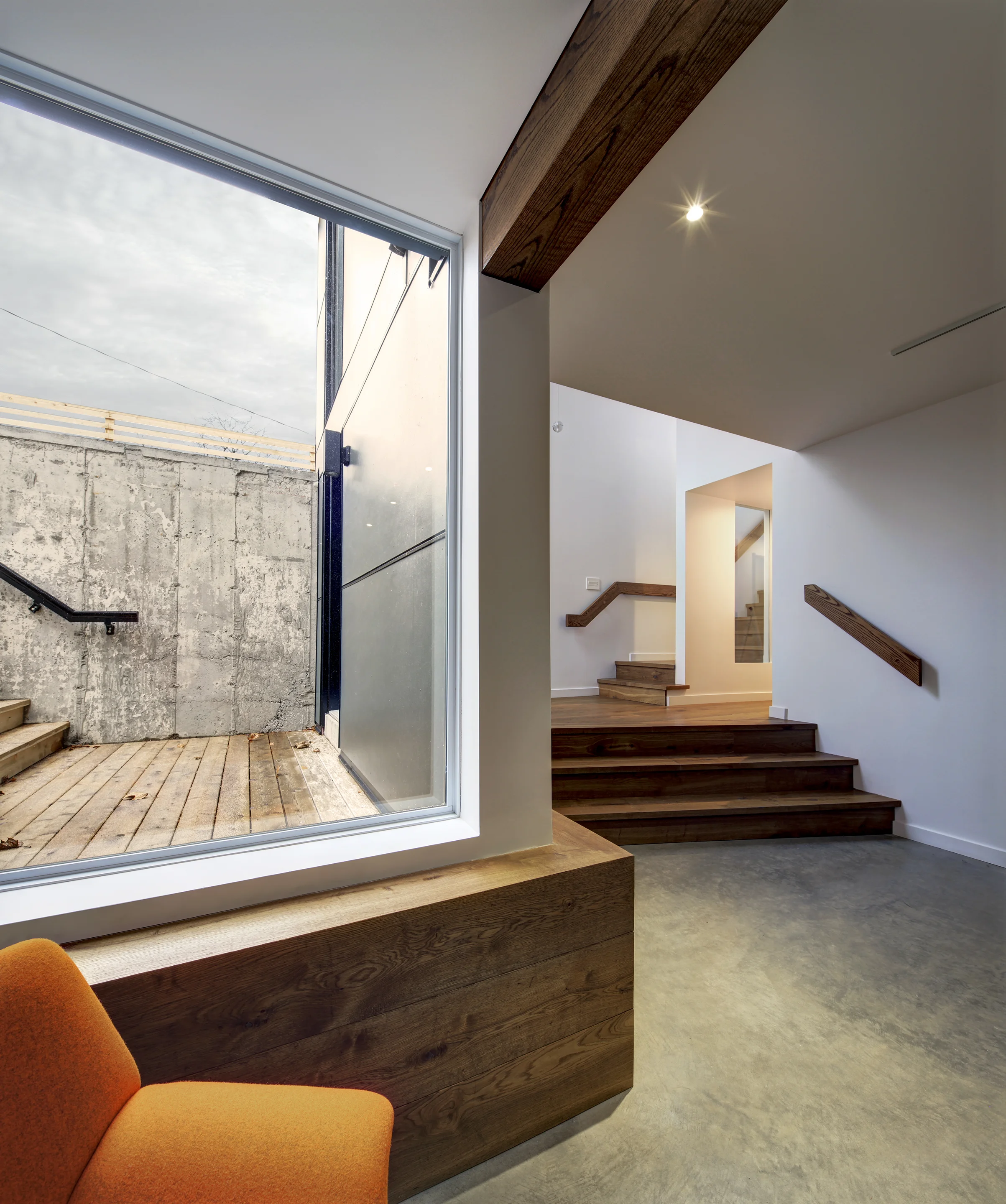 Interior view of corner studio space with wooden details, orange accents, and concrete and glass mediums throughout inside The Borg additions