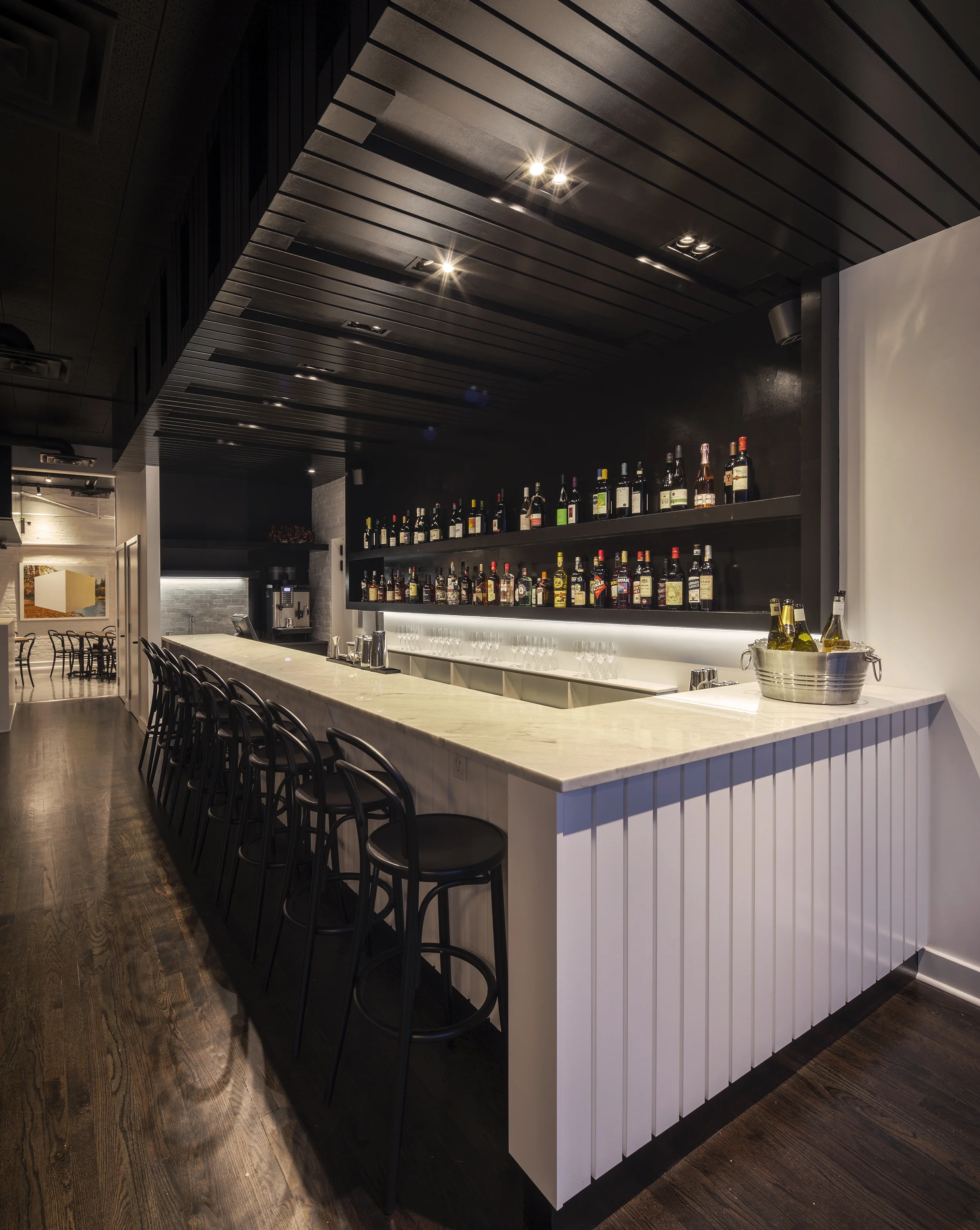 View of new Citizen bar design with white marble bar top, white side panels and above dark panels with lighting