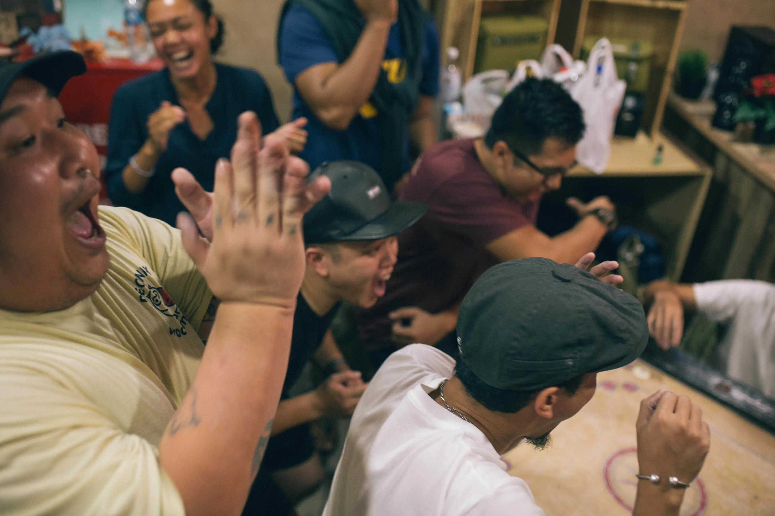 People sitting around a table laughing and enjoying themselves, engaging in a lively social gathering indoors.