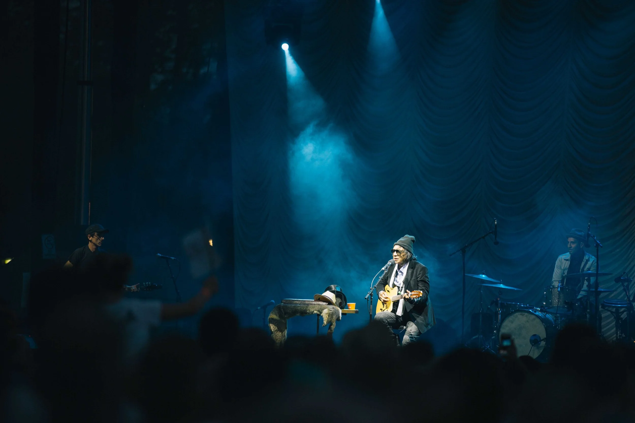 Musician performing on stage with guitar under blue lighting