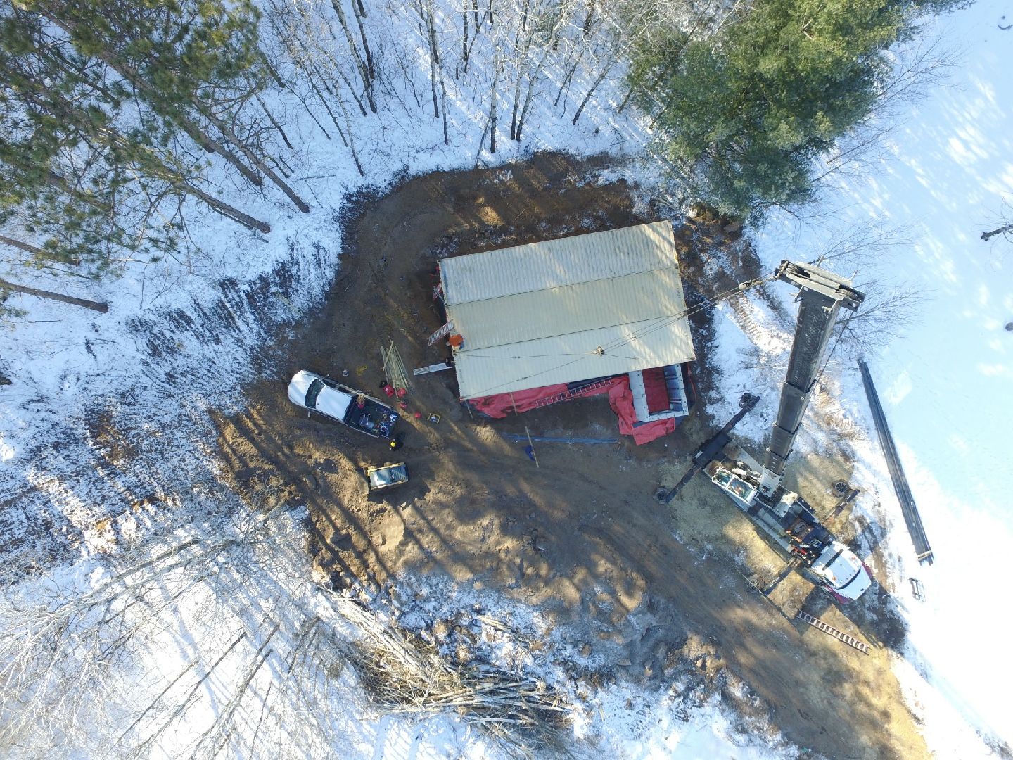 Drone view of 3 container sitting on the foundation of a house with the crane next to the house