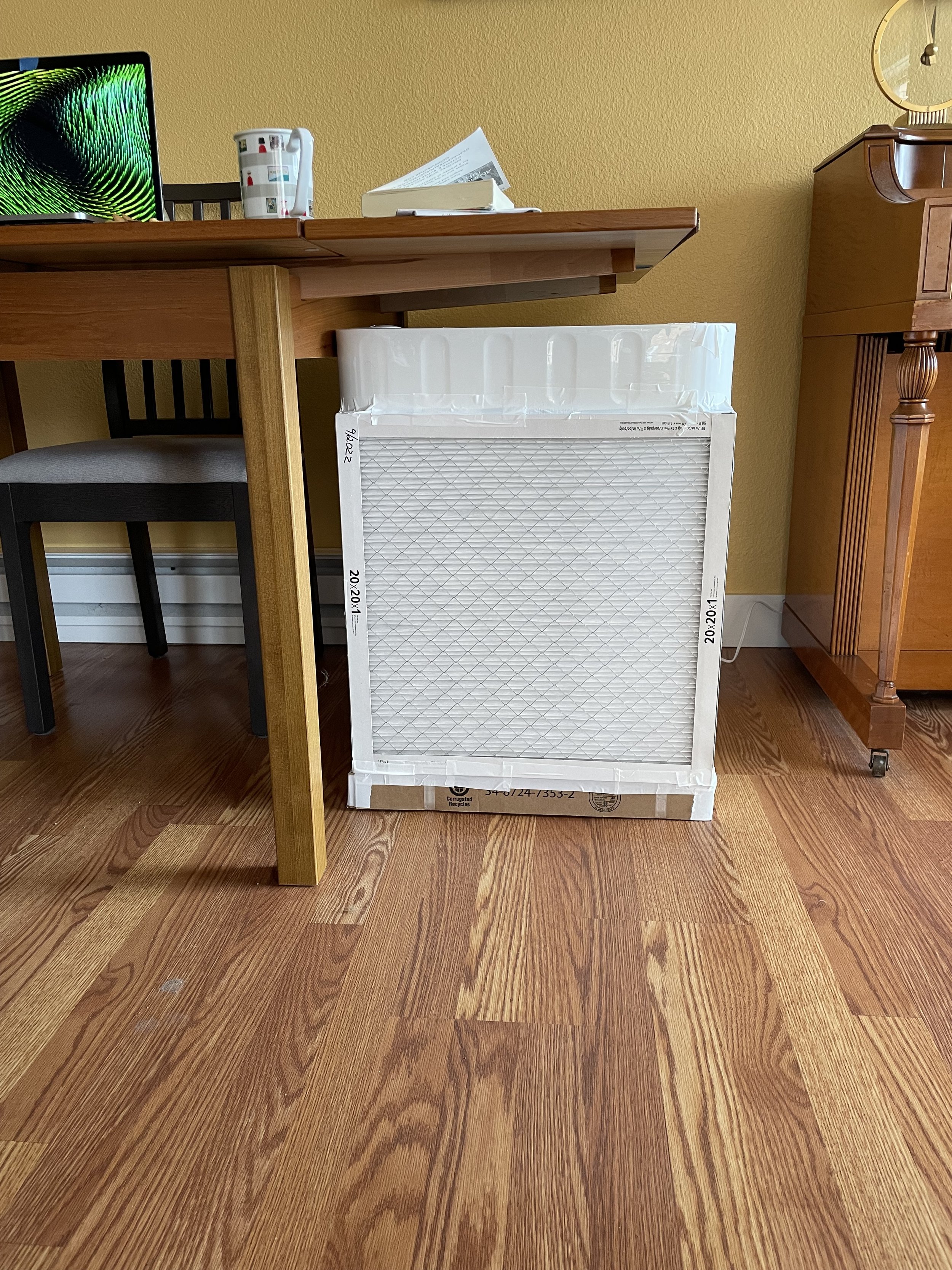 A box made of 4 air filters and a box fan on top secured by white duct tape.