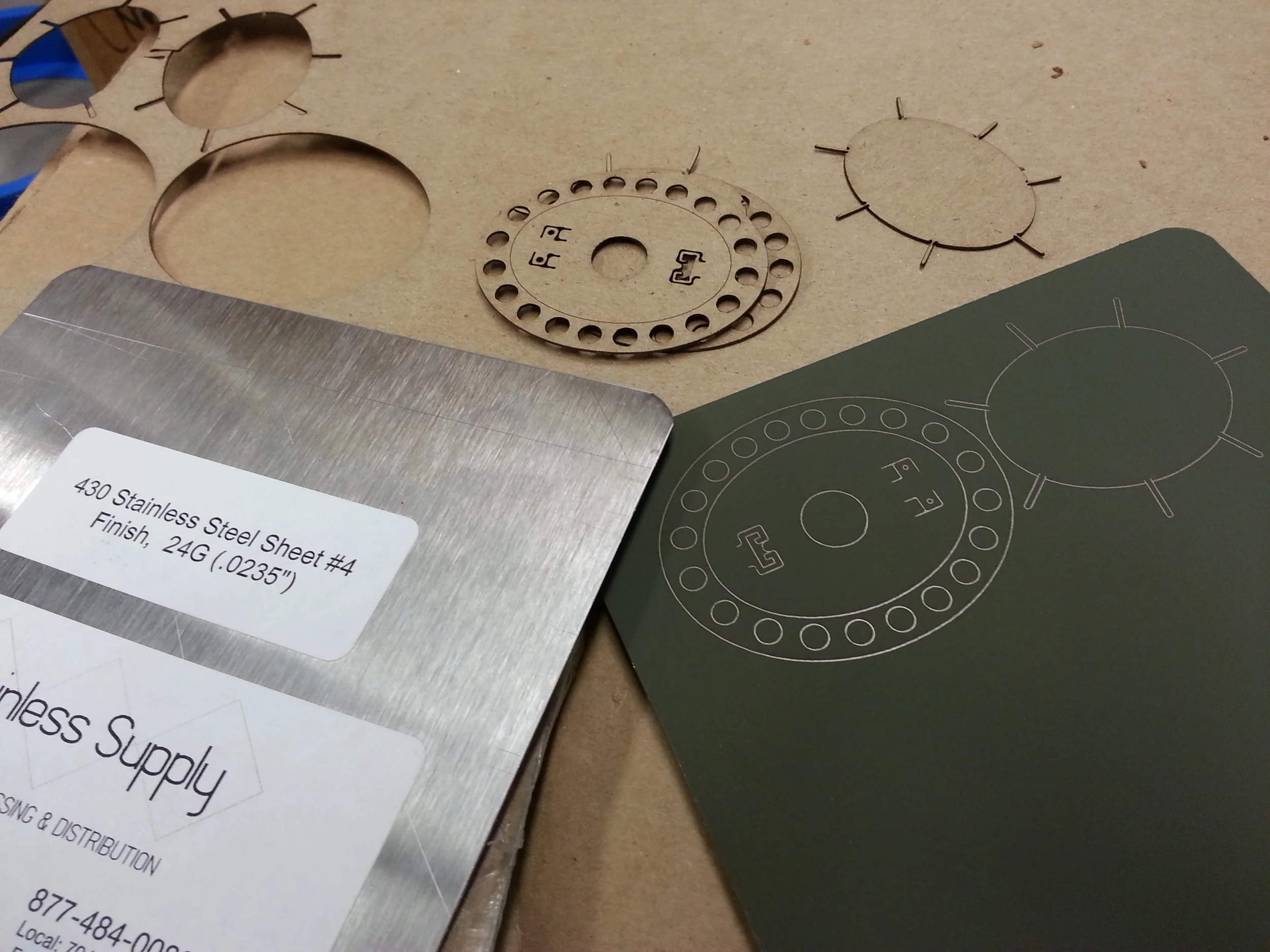 Steel samples, laser cut chipboard test samples, and the patterns transferred onto steel for testing.