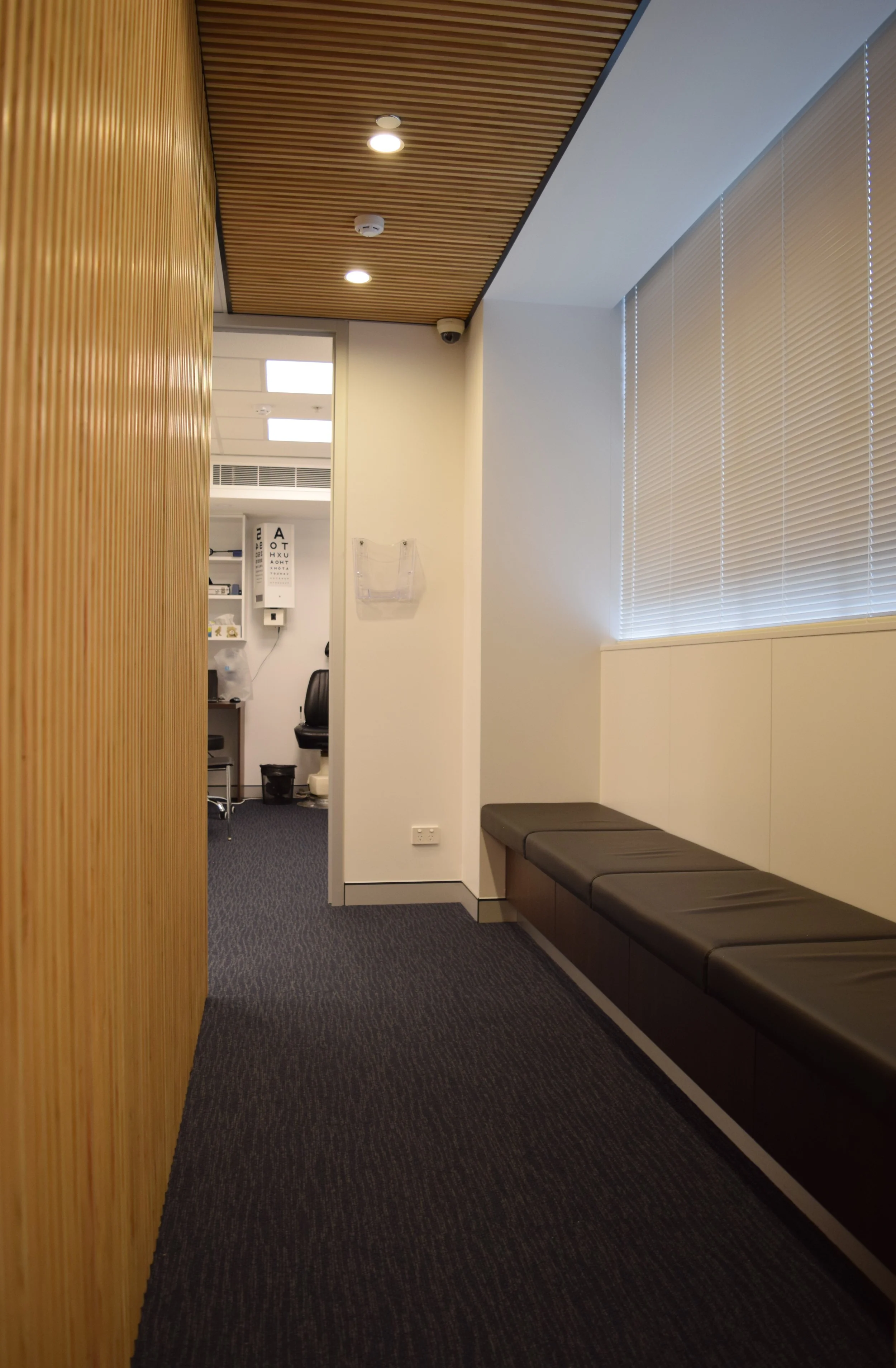  Day-lit corridor hugs the glazed perimeter whilst the venetians provide screening. Fixed seating for patients being dialated with storage drawers below. 