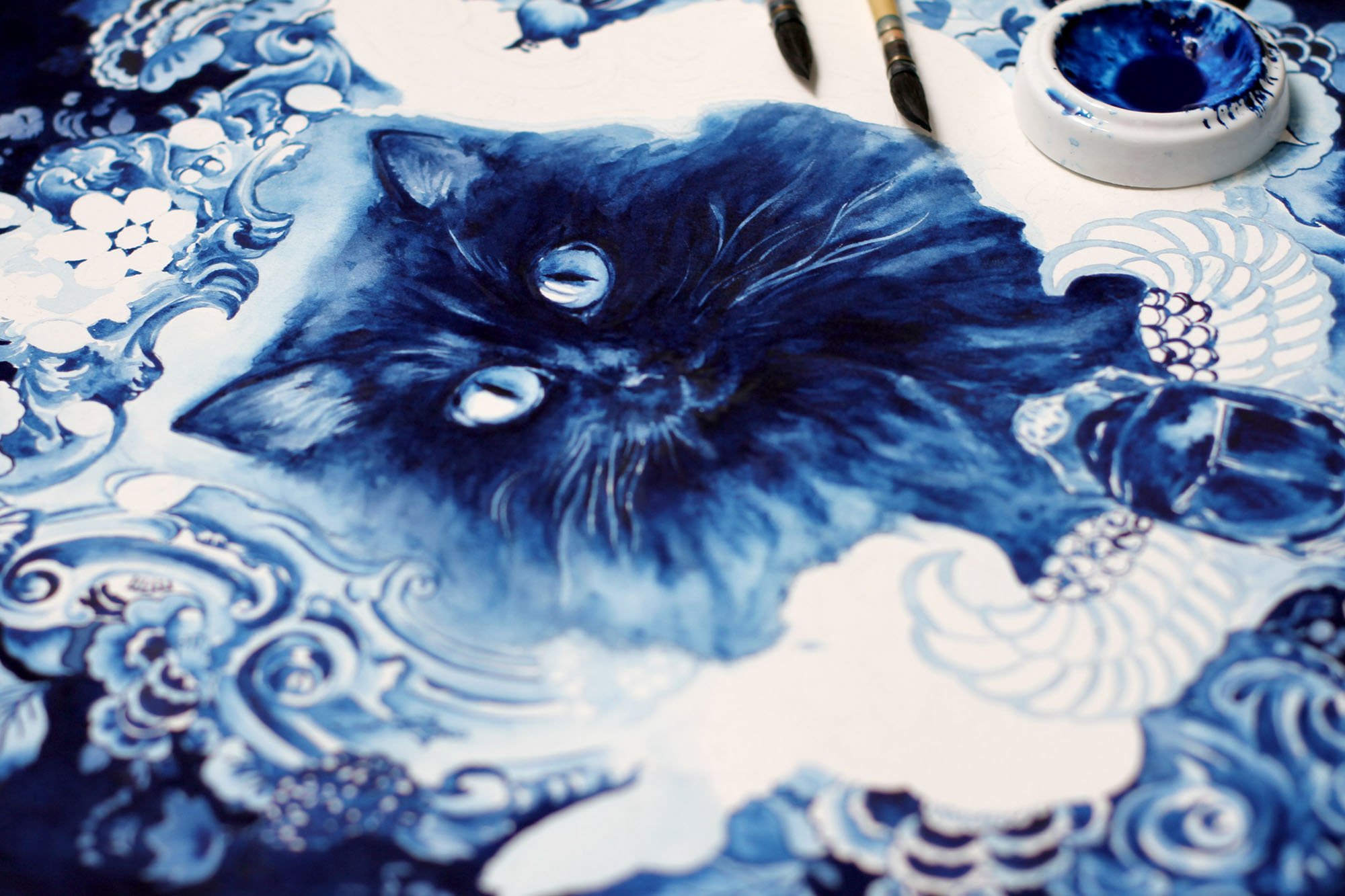Detail of the Behemoth painting in progress, showing the expressive black cat portrait emerging from layered Delft Blue watercolor washes, ornamental patterns, and mixed-media techniques.