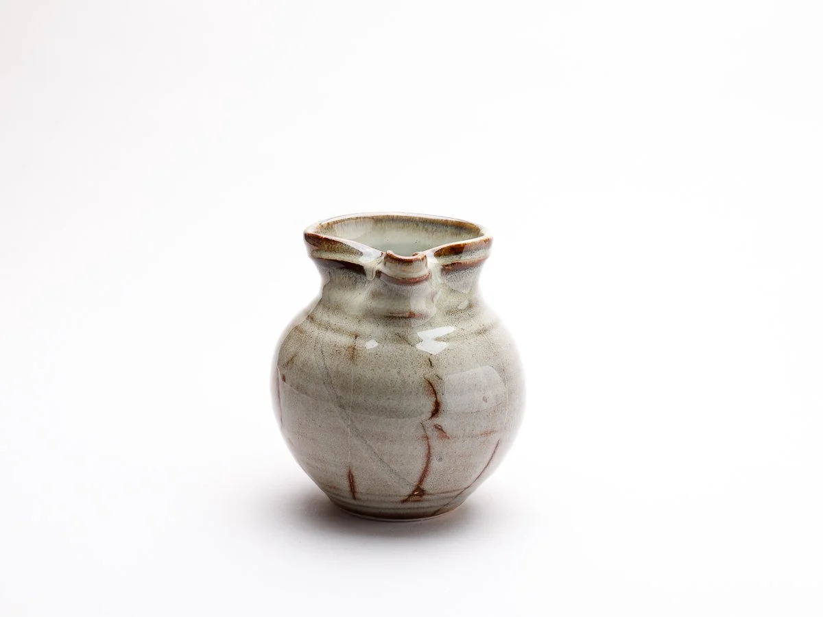 creamy white jug with brown and orange details with detailed handle and spout
