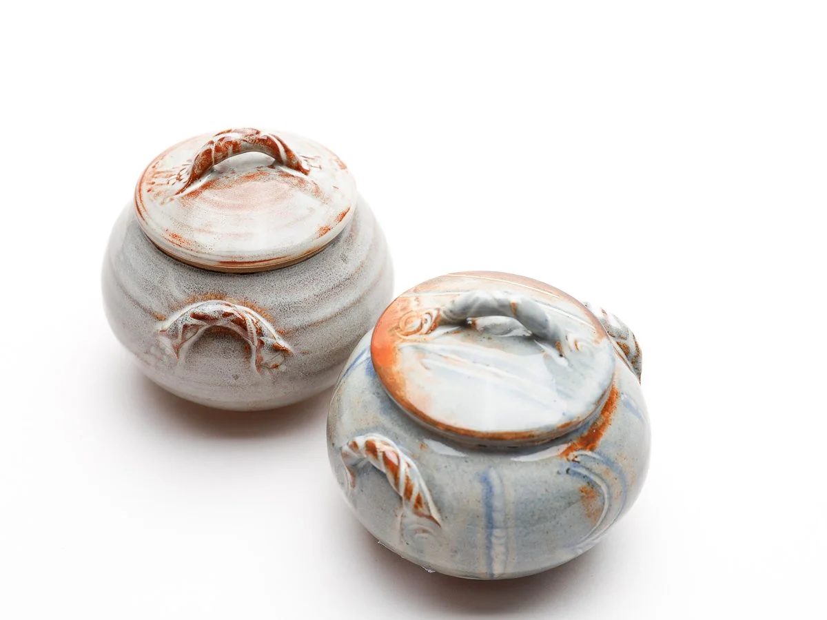 Small trinket box with twisted detailed handle, in a  creamy white glaze with orange details