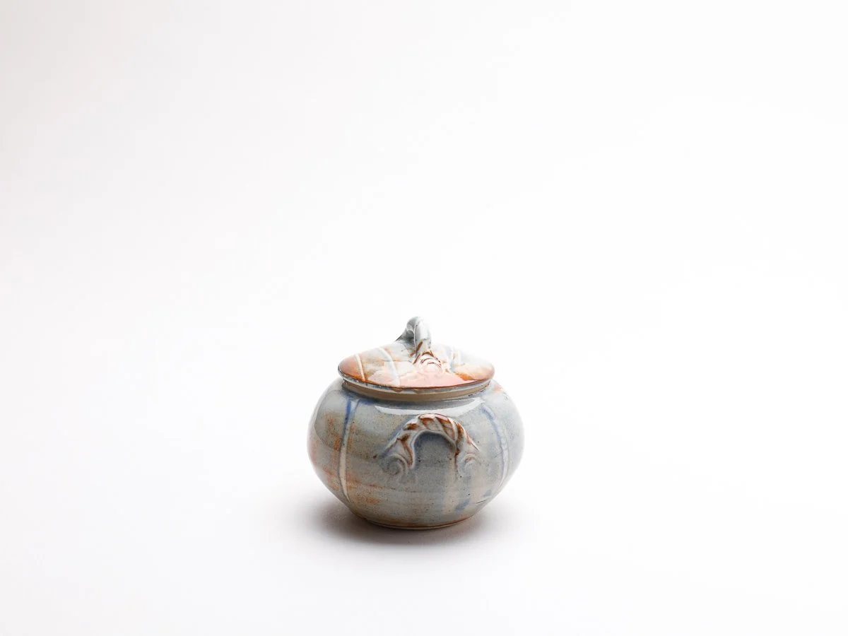 Small trinket box with twisted detailed handle, in a  creamy white glaze with orange details
