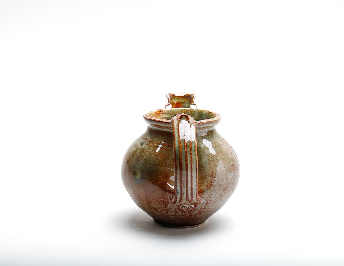 orangey-green-yellow jug with short pourer and detailed handle