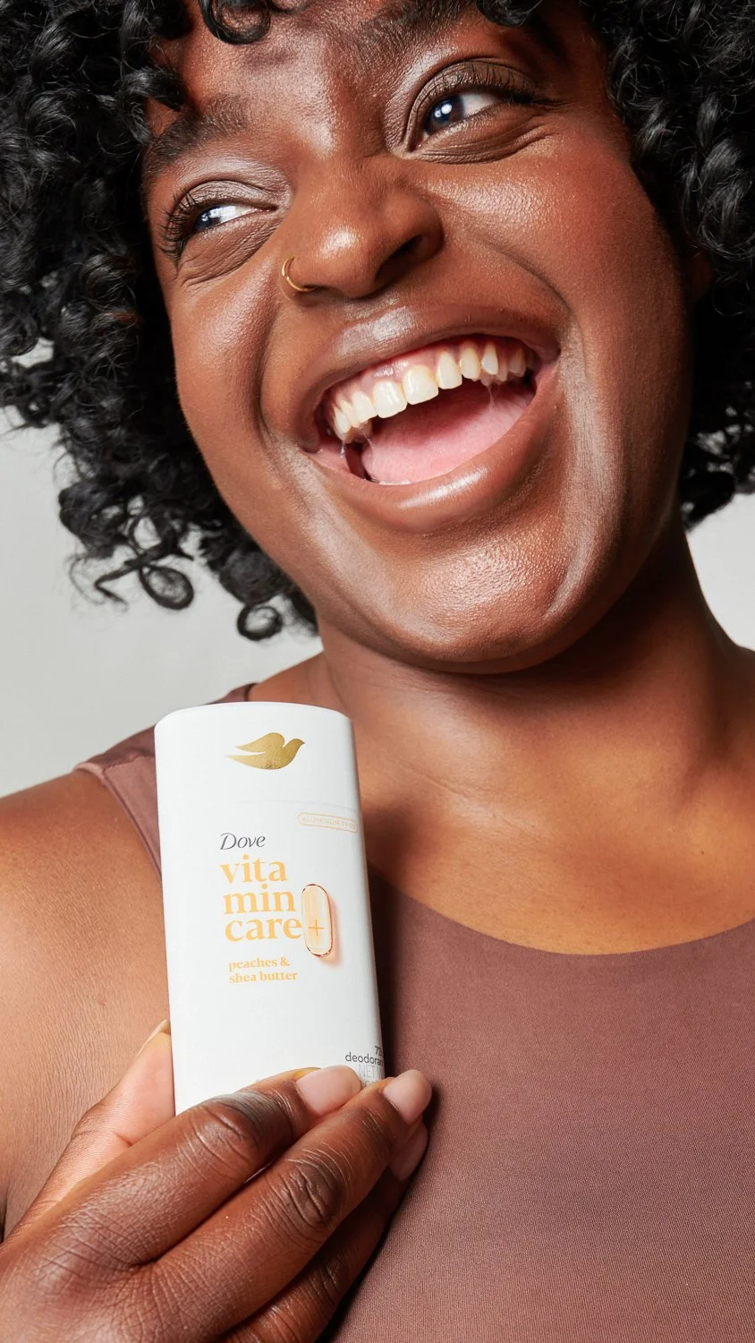 Real Beauty Campaign for Dove. Smiling black woman holding deodorant looking away from camera
