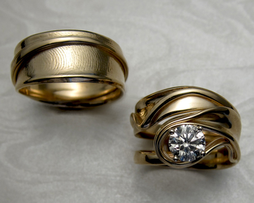 Matching free-form wedding set with ladies fingerprint on gents band. 14k yellow gold, diamond set in 4-prong setting.