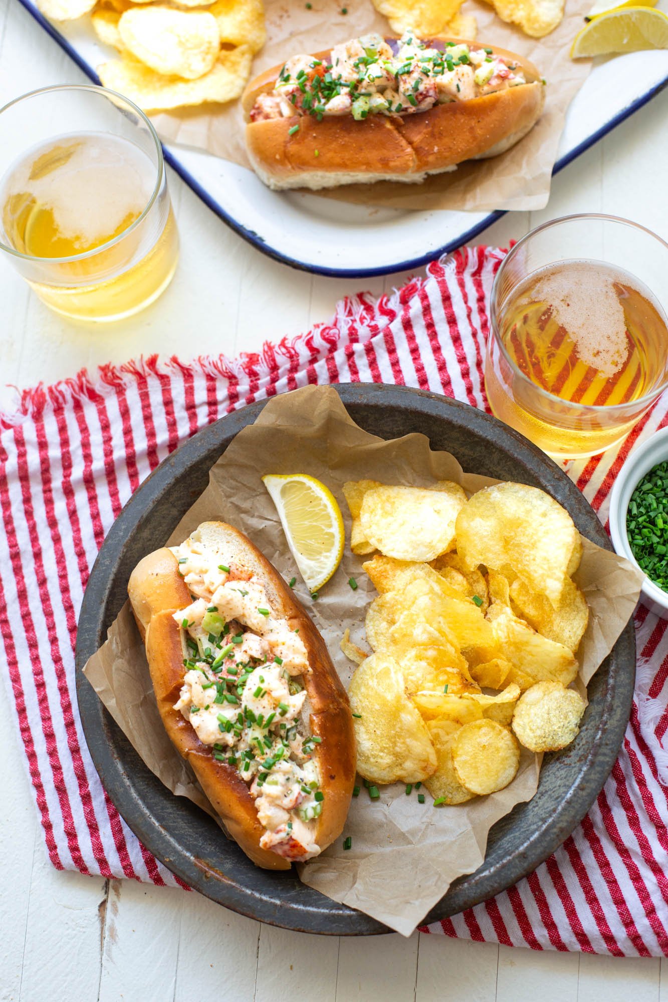 A plate with grilled Cajun lobster roll and some chips.