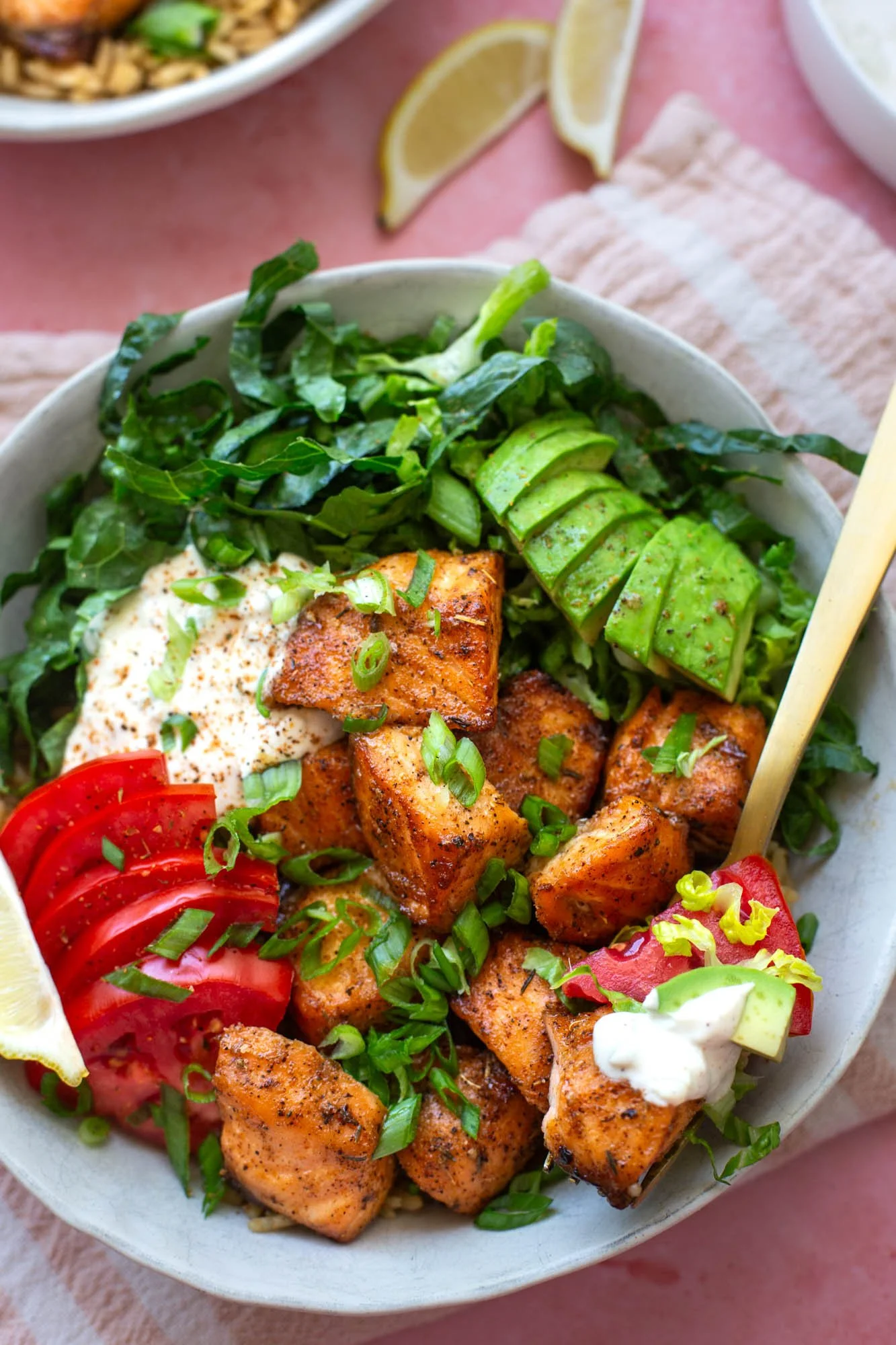 A bowl of blackened salmon with rice and fresh veggies.