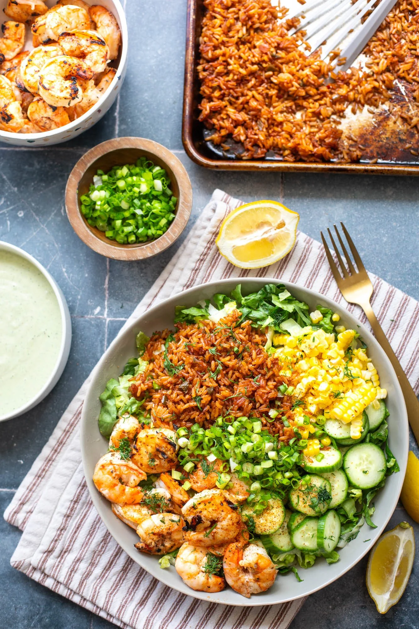 Cajun grilled shrimp served over crispy rice with fresh vegetables and creamy dressing in a summer salad bowl.