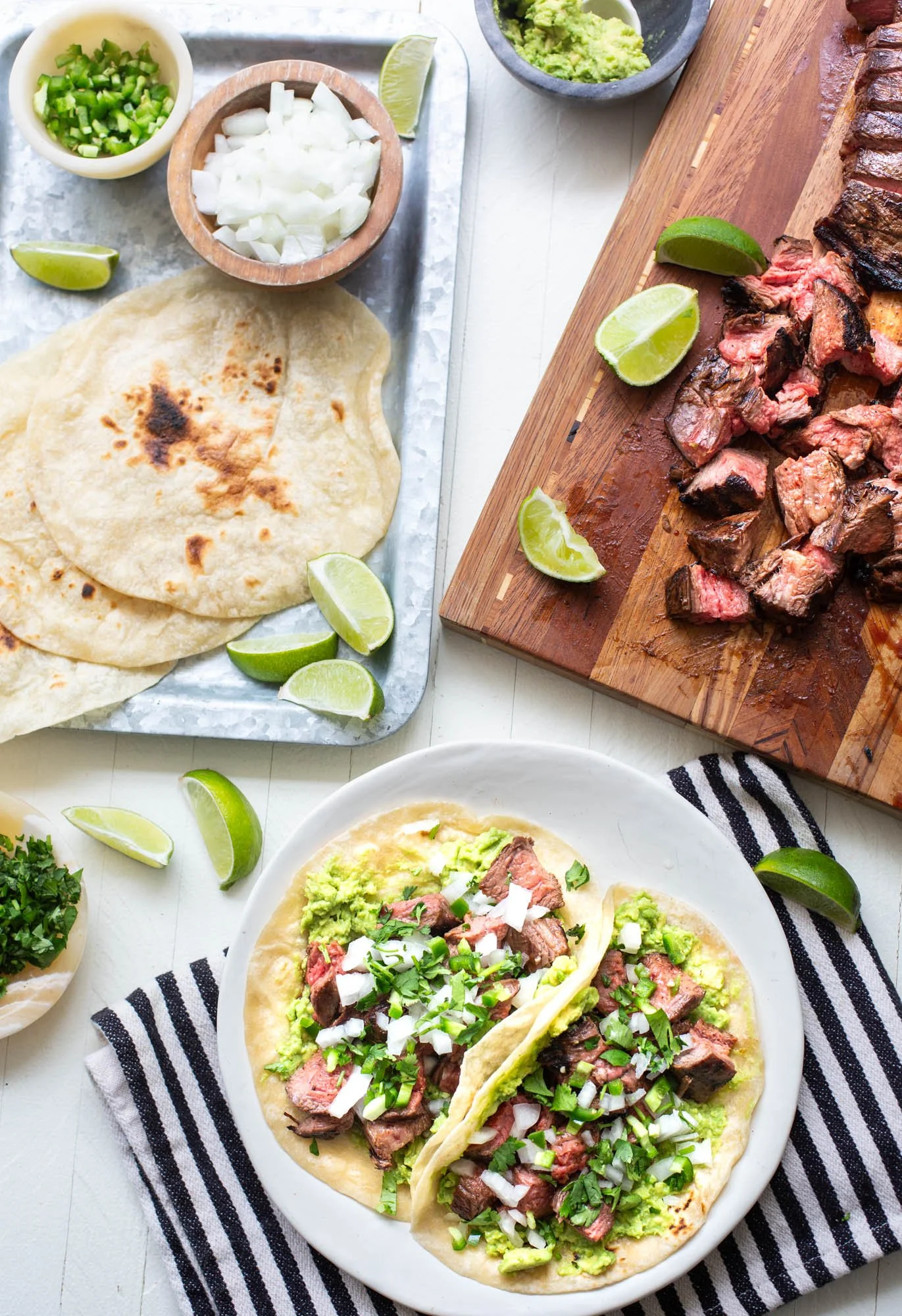 Carne Asada taco ingredients laid out along with plated tacos.