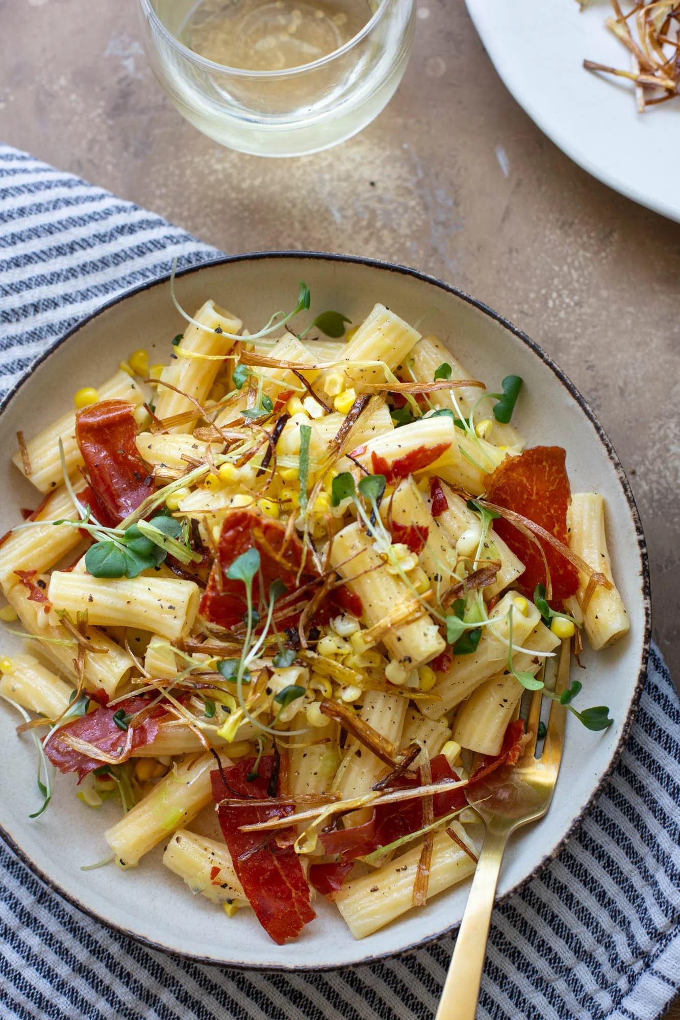 A bowl of summer pasta with corn, leeks, and crispy prosciutto.