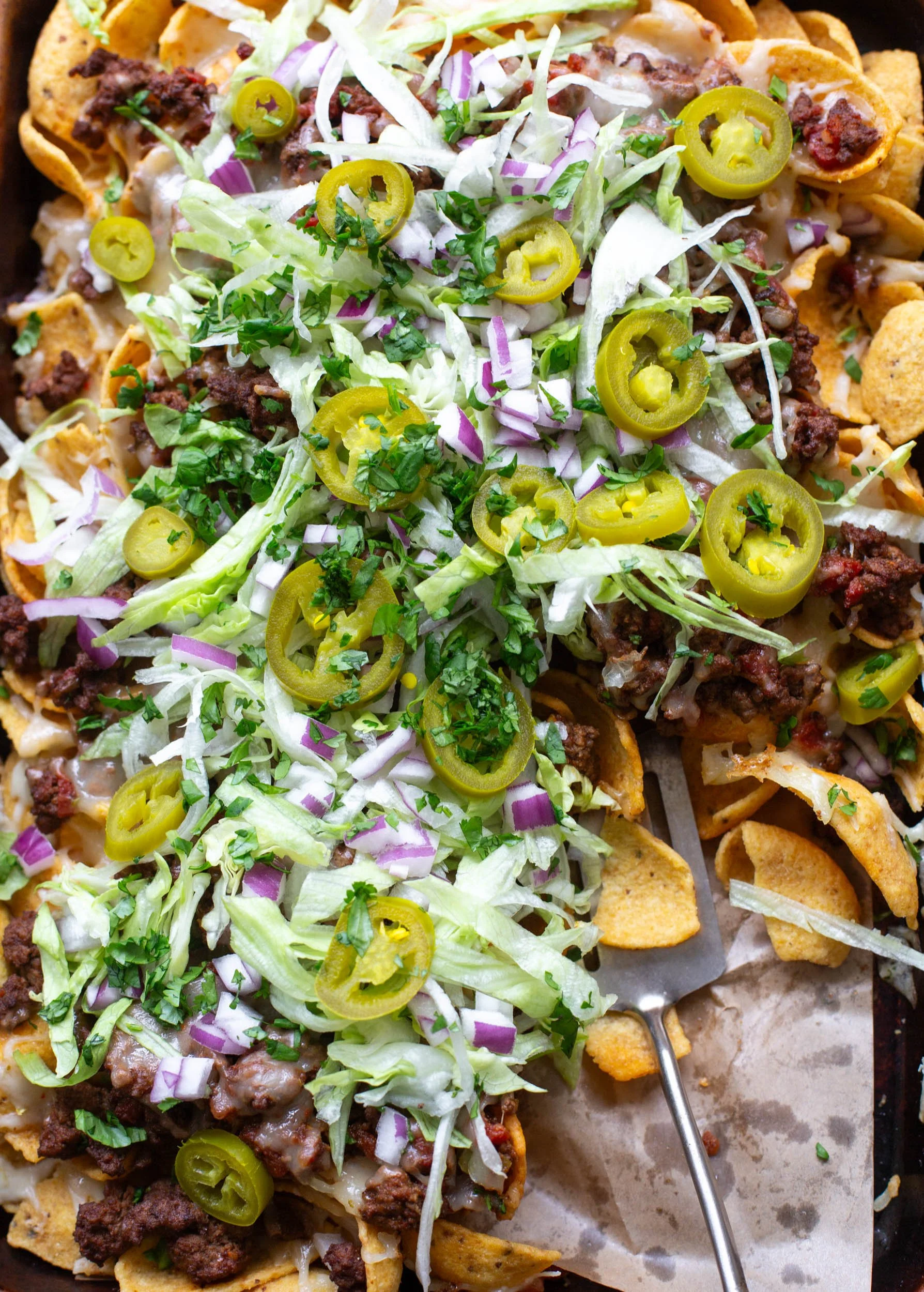 Walking tacos made on a sheet pan with corn chips and served with fresh toppings.