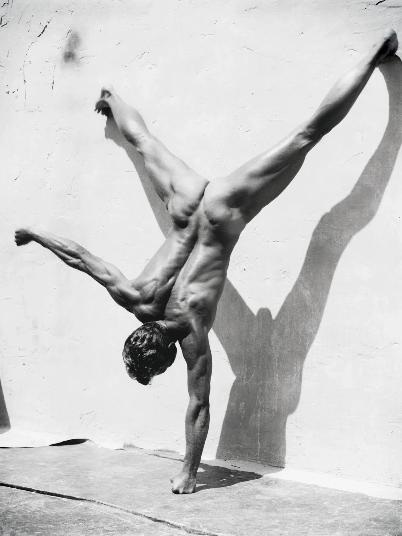 Nude man doing a hand stand