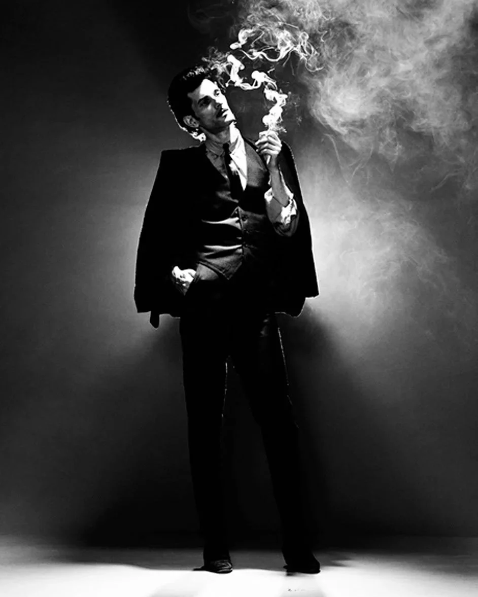 Mink de Ville smoking in front of a spotlight