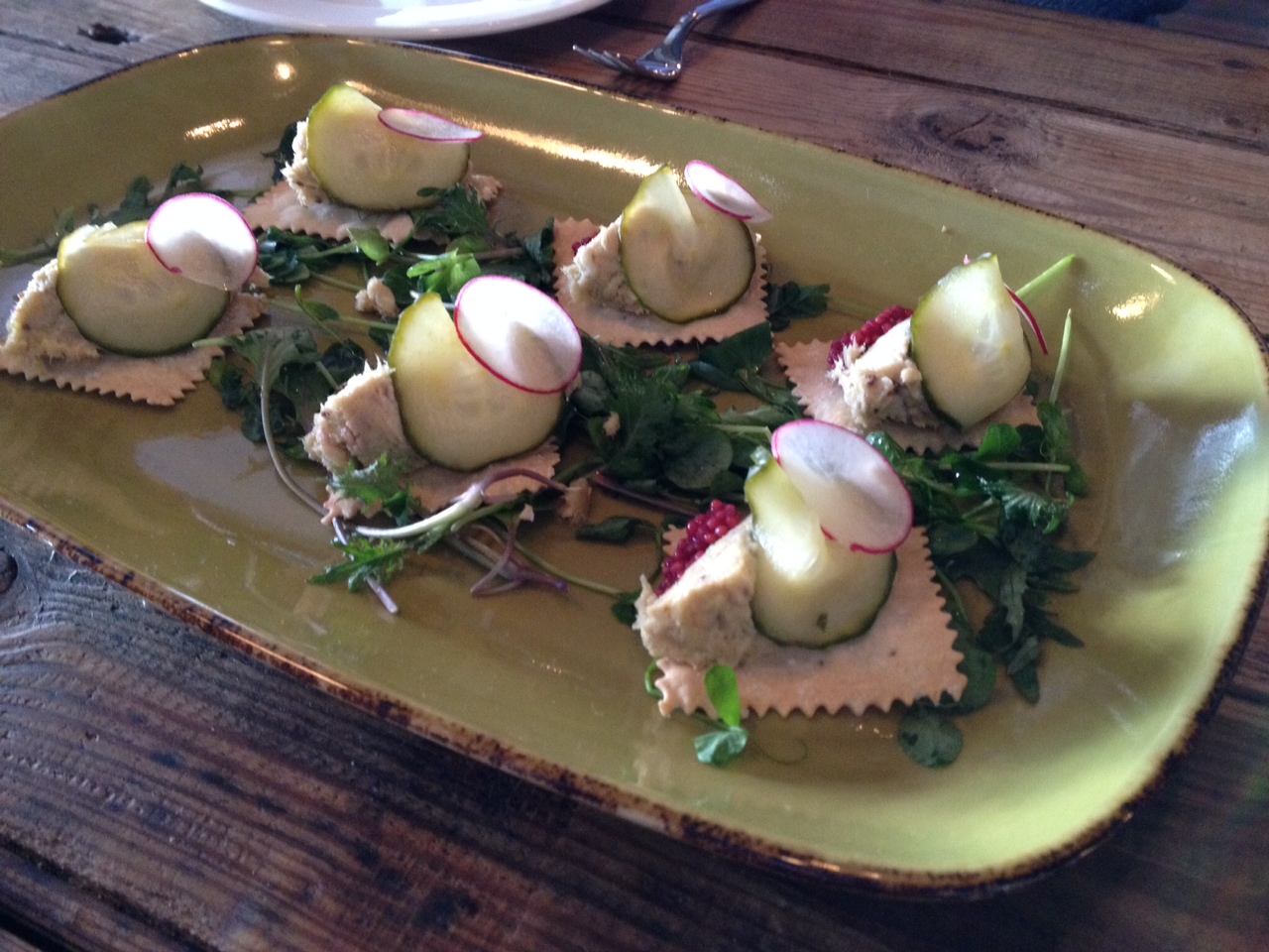 Sturgeon rillettes on house made crackers, with pickles on a bed of pea shoots