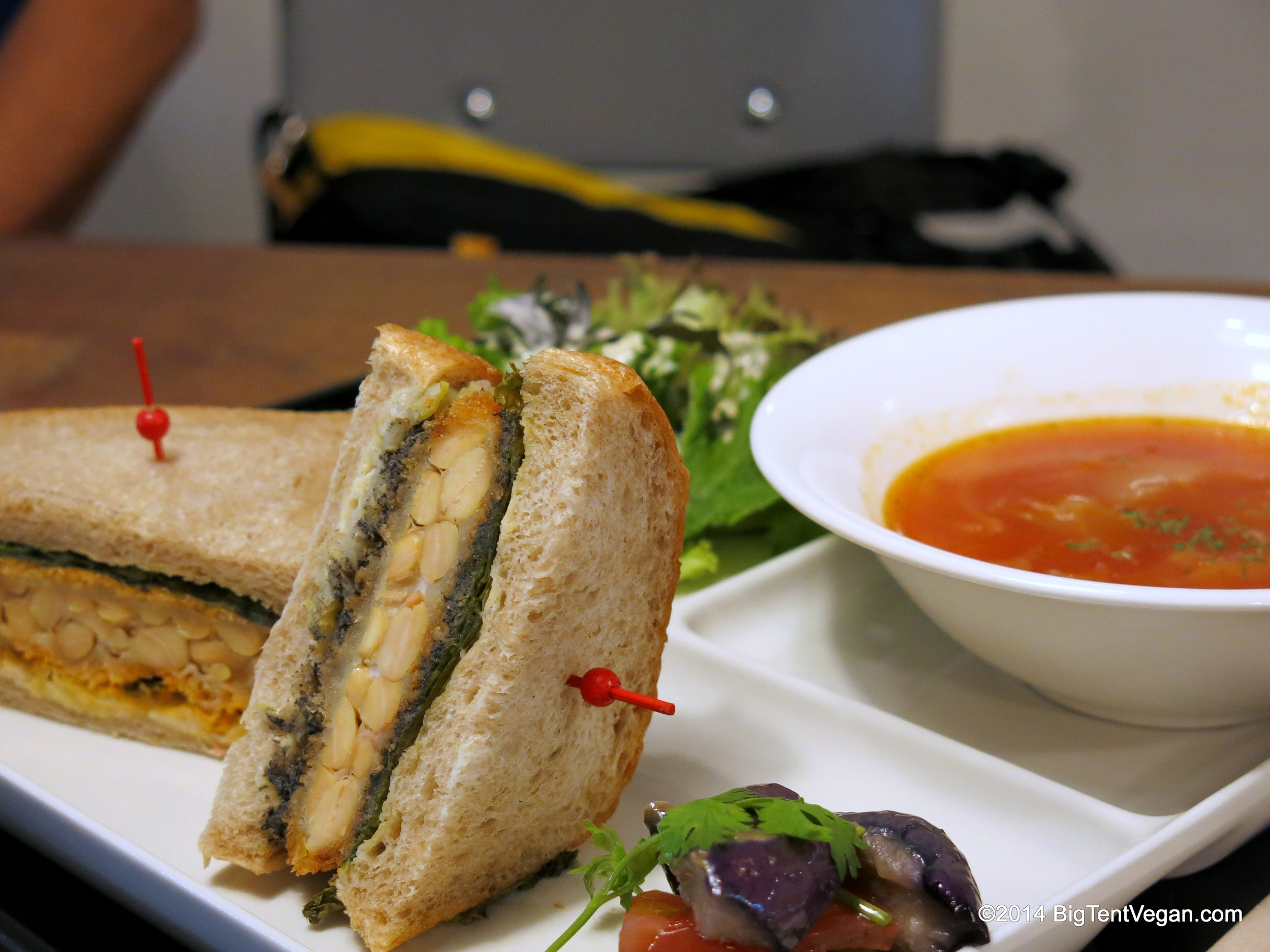 Deep-fried Crispy Tempeh Sandwich with Fresh Green Salad, Tomato Soup, and Pickled Eggplant. Notice each half-sandwich came with a different spread...one had a green pesto spread, and the other a pinkish tomato spread.