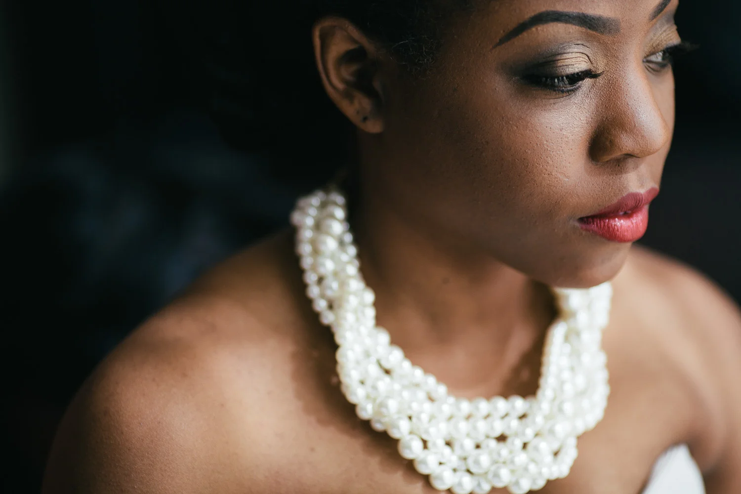 Portrait of a bride in soft light wearing a pearl necklace