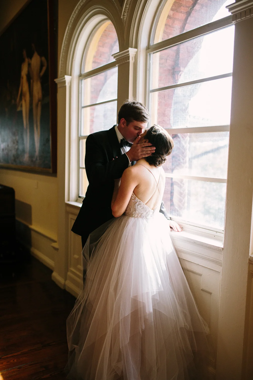 Bride and groom kissing by the window of Lighter Museum in Saint Augustine