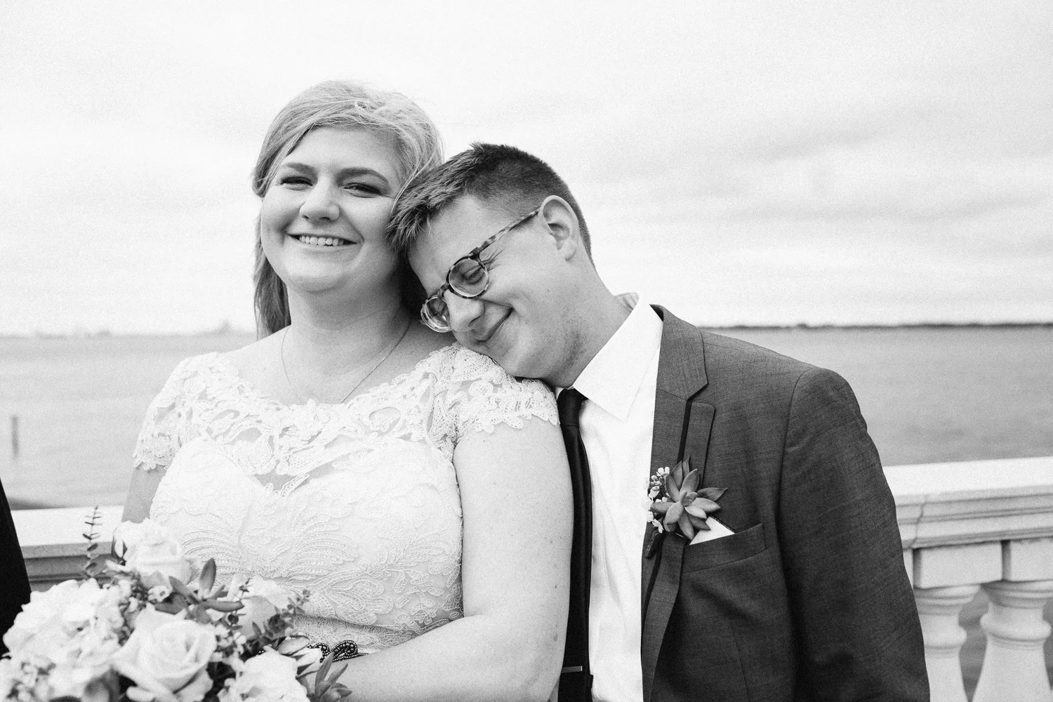 Smiling groom rests his head on bride's shoulder by the docks at Florida Yacht Club in Jacksonville