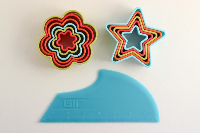 Clockwise from top: flower cookie cutters , star cookie cutters , and scraper . 