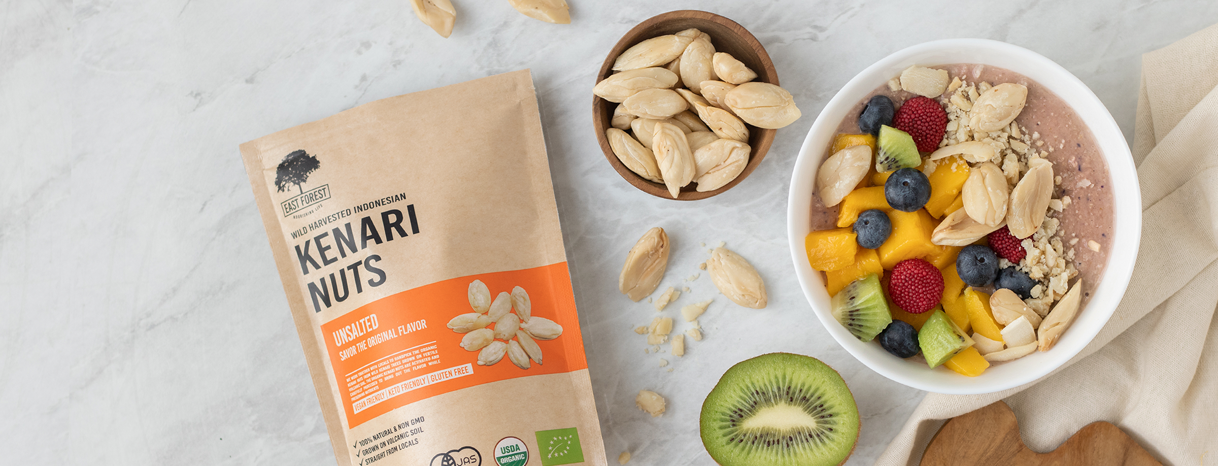 East Forest Unsalted Kenari Nuts with Kenari kernels and a fruit bowl — East Forest Kenari Nuts (Kawanasi)
