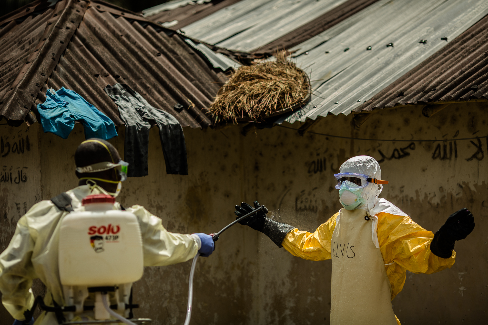  Bong County, Liberia - October 9, 2014: A member of the International Medical Corps (IMC)&nbsp;Ebola response team gets sprayed with chlorine after going into a family home in Mawa Town to check on an elderly woman who is sick after several members 
