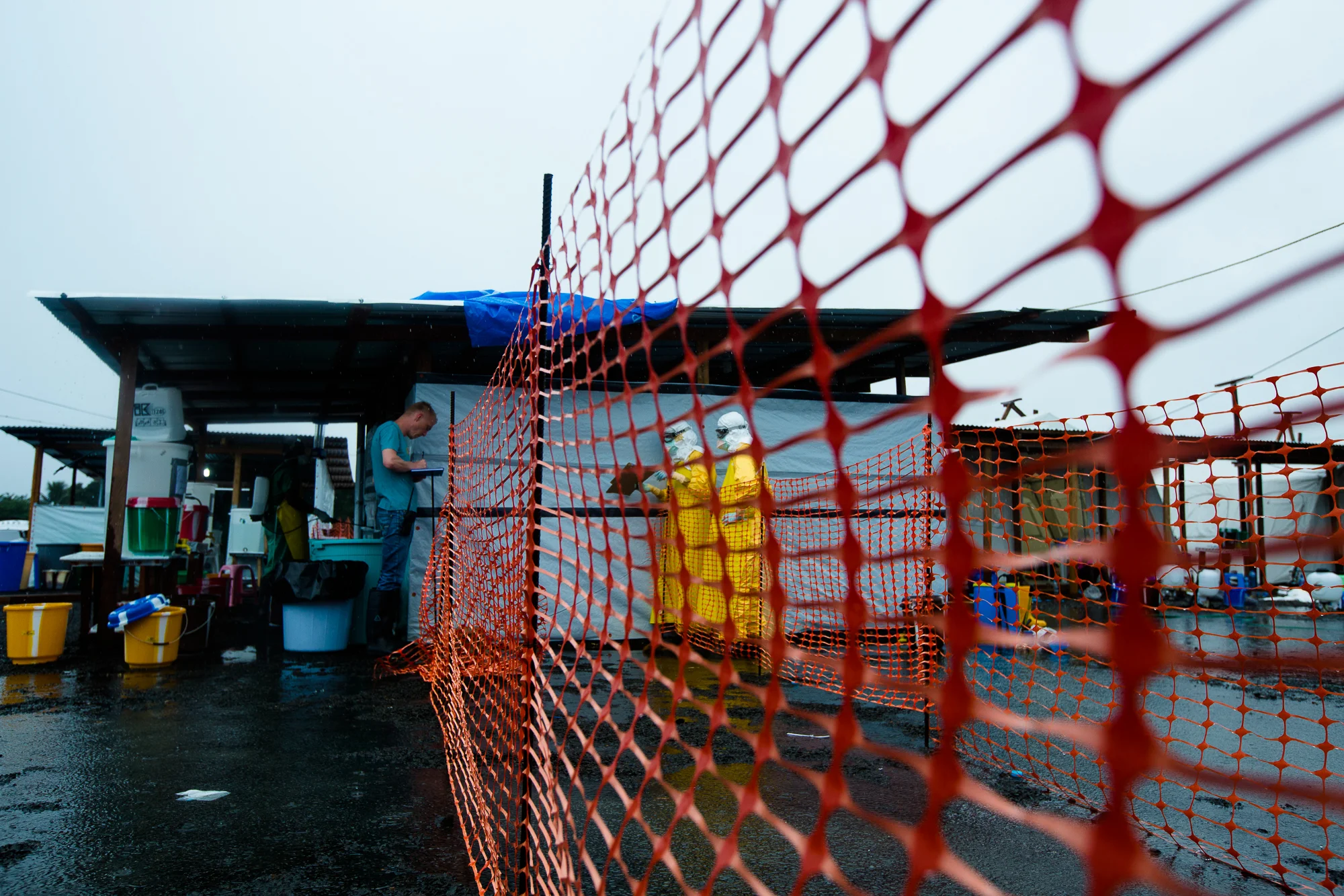  Monrovia, Liberia - Aug 30, 2014: &nbsp;Health workers in Personal Protective Equipment inside the Ebola hot zone&nbsp;yell observations from patient rounds across the fence to Jens Pederson, a nurse with Doctors Without Borders (MSF), because paper
