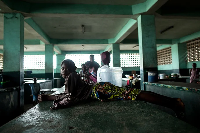  Hana, who sells donuts, lays across a counter once filled with meat products for sale in Monrovia, Liberia, on August 18, 2014. Waterside Market is typically a bustling commerce center in downtown Monrovia. Now, with fears of Ebola, vendors are stru