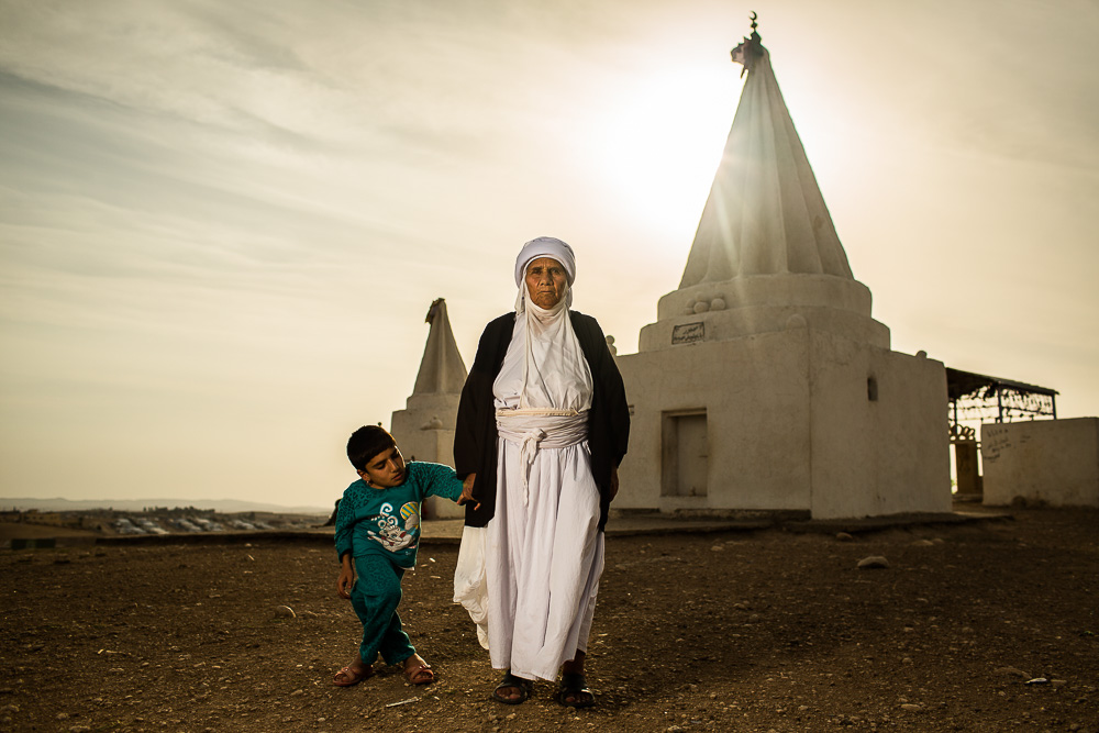  "Everyday I come here and I ask God if anyone can help us."&nbsp;   Adul, 60, stands with her deaf and mute granddaughter Rajja, 14, in front of the Baba Chawish Yazidi temple outside of the Khanke refugee camp.  