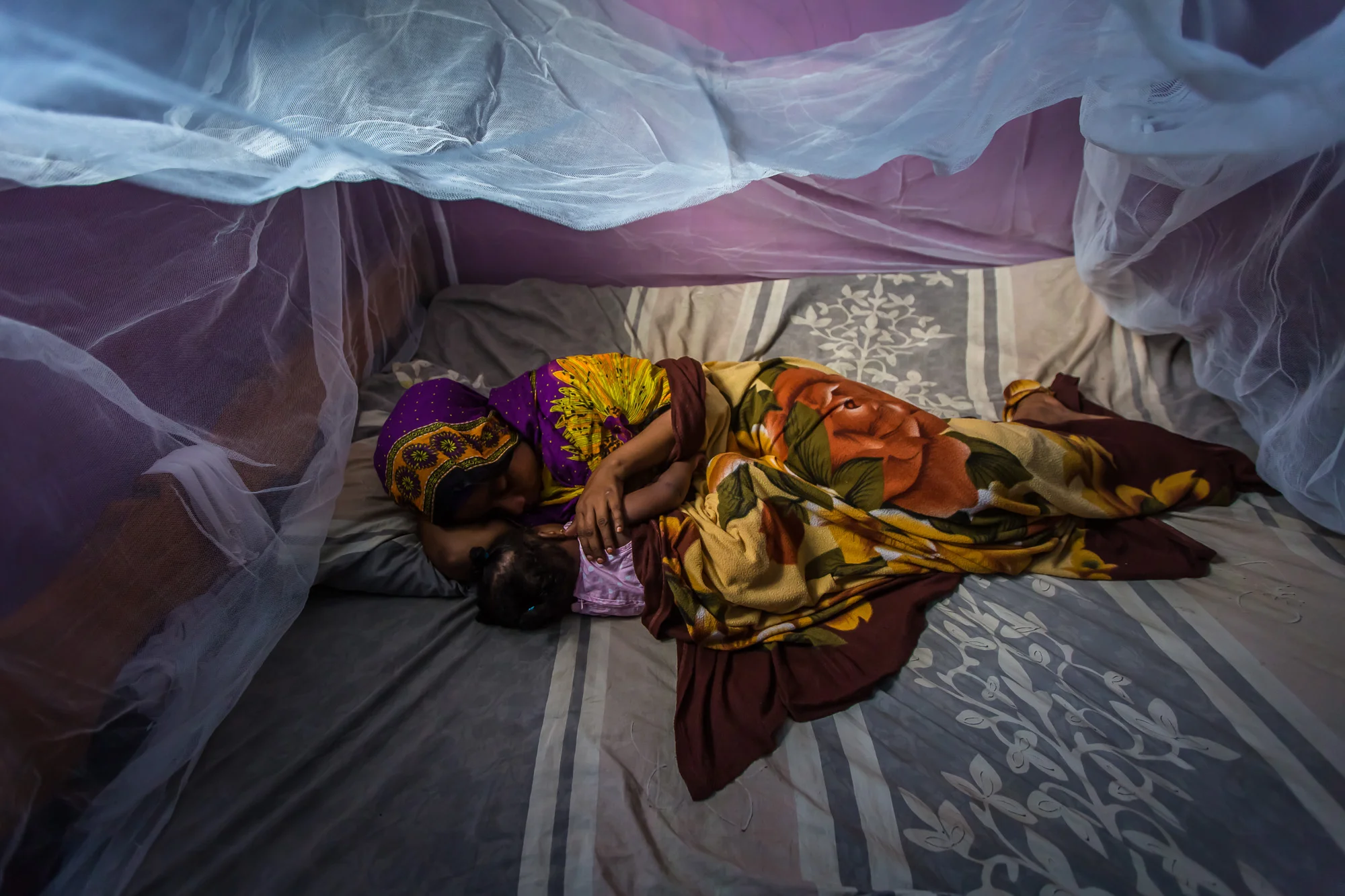  Habiba Suleiman, 28, a District Malaria Surveillance Officer (DMSO) lies under a bed net with her daughter at their home in Zanzibar, Tanzania. 