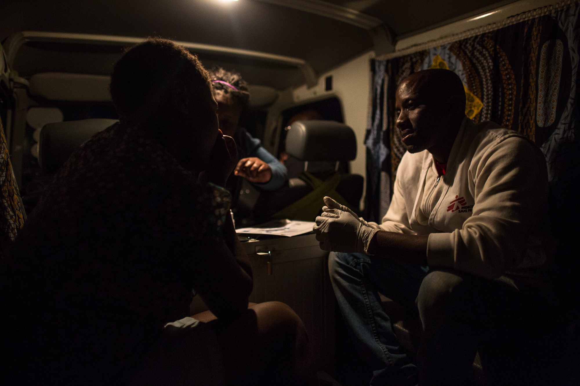 MSF peer educator, Constantino, tests a comercial sex worker for HIV, yellow fever and Syphilis while Patti, another MSF peer educator, counsels her inside of the MSF vehicle in her neighborhood. She was last tested in 2014, but this is the first time she's been tested by MSF. This time she tested negative for HIV and yellow fever, but positive for syhpillis.