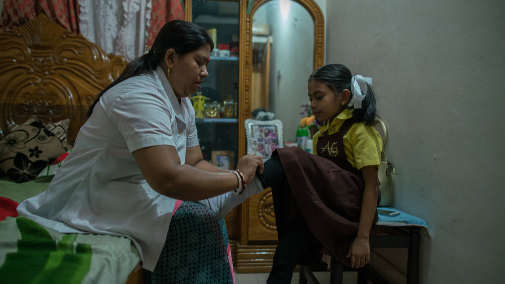  Shanta Das, a paramedic at Smiling Sun Clinic, helps her daughter, Ankita, get ready for school in the morning. 