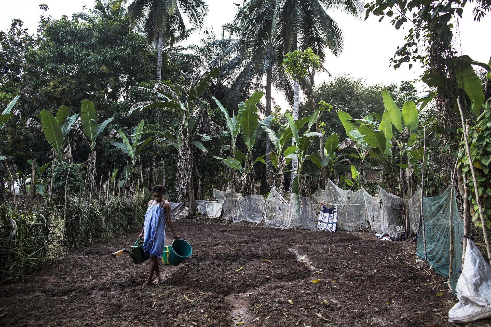  Mariatu Bangura, 18, of Rokupr, waters her garden near her house. She recently started the garden so that she can make more money to provide for her son and herself.&nbsp; 