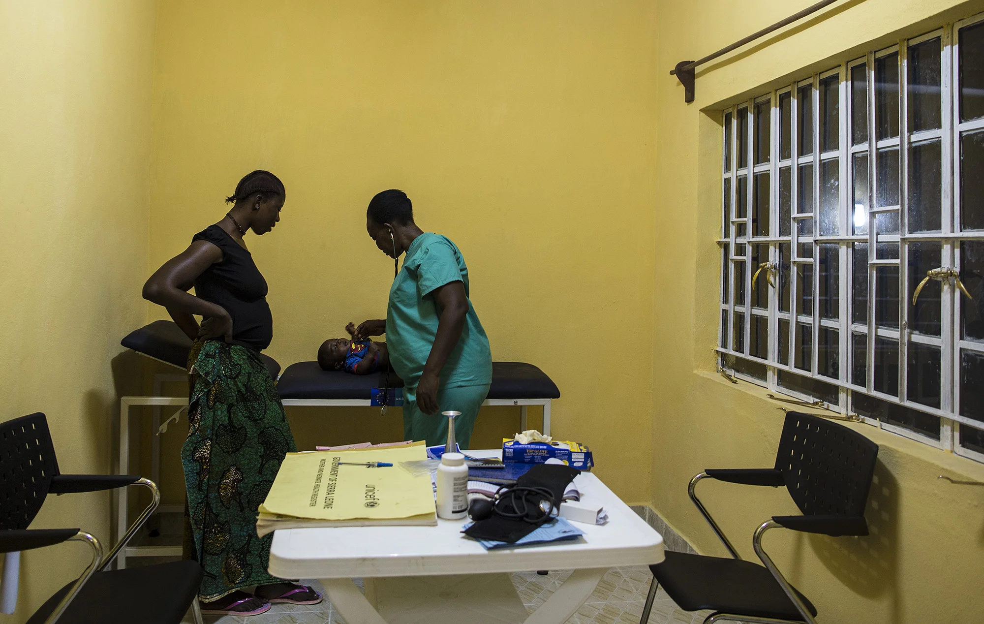 Zainab Tity Sawaneh, Maternal and Child Health Aide, right, examines a patient during the evening. Konsho CHP is now equipped with solar power.&nbsp; 