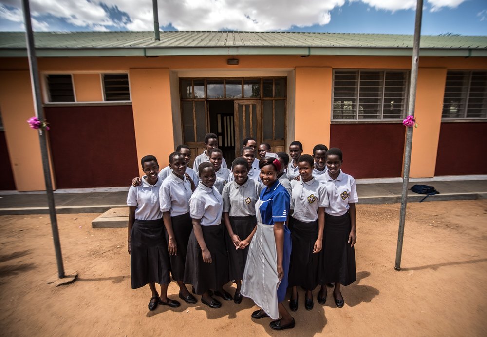  Students on Intrahealth-funded scholarships at the Matany School of Nursing and Midwifery in Karamoja, Uganda, pose for a picture in front of the school building. 