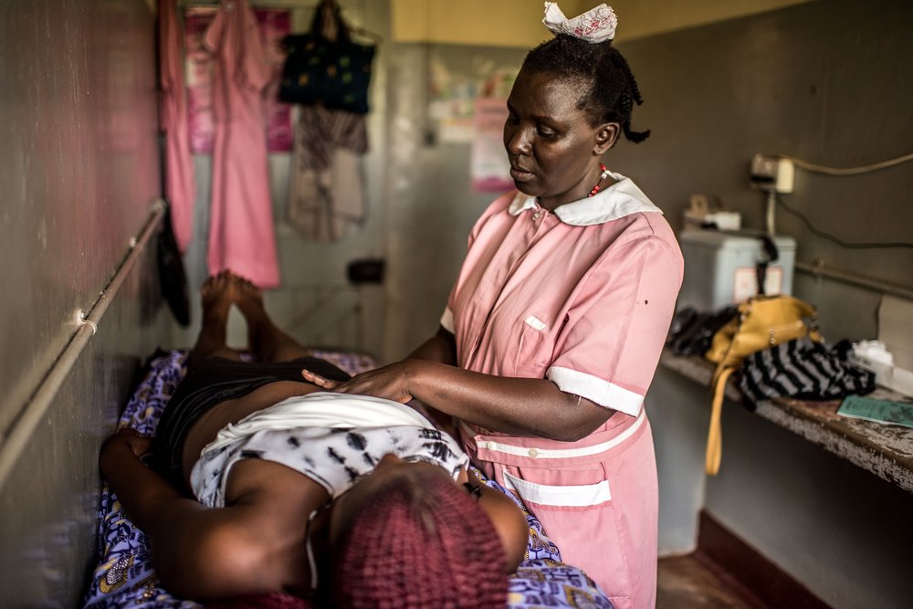  Enrolled midwife Kayuma Jane performs a check-up on a pregnant woman, Kelea Kakamazi, at the Jinja Regional Referral Hospital in Jinja, Uganda. 